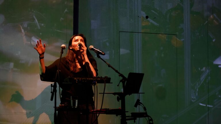 A singer on the stage with projections in the background.