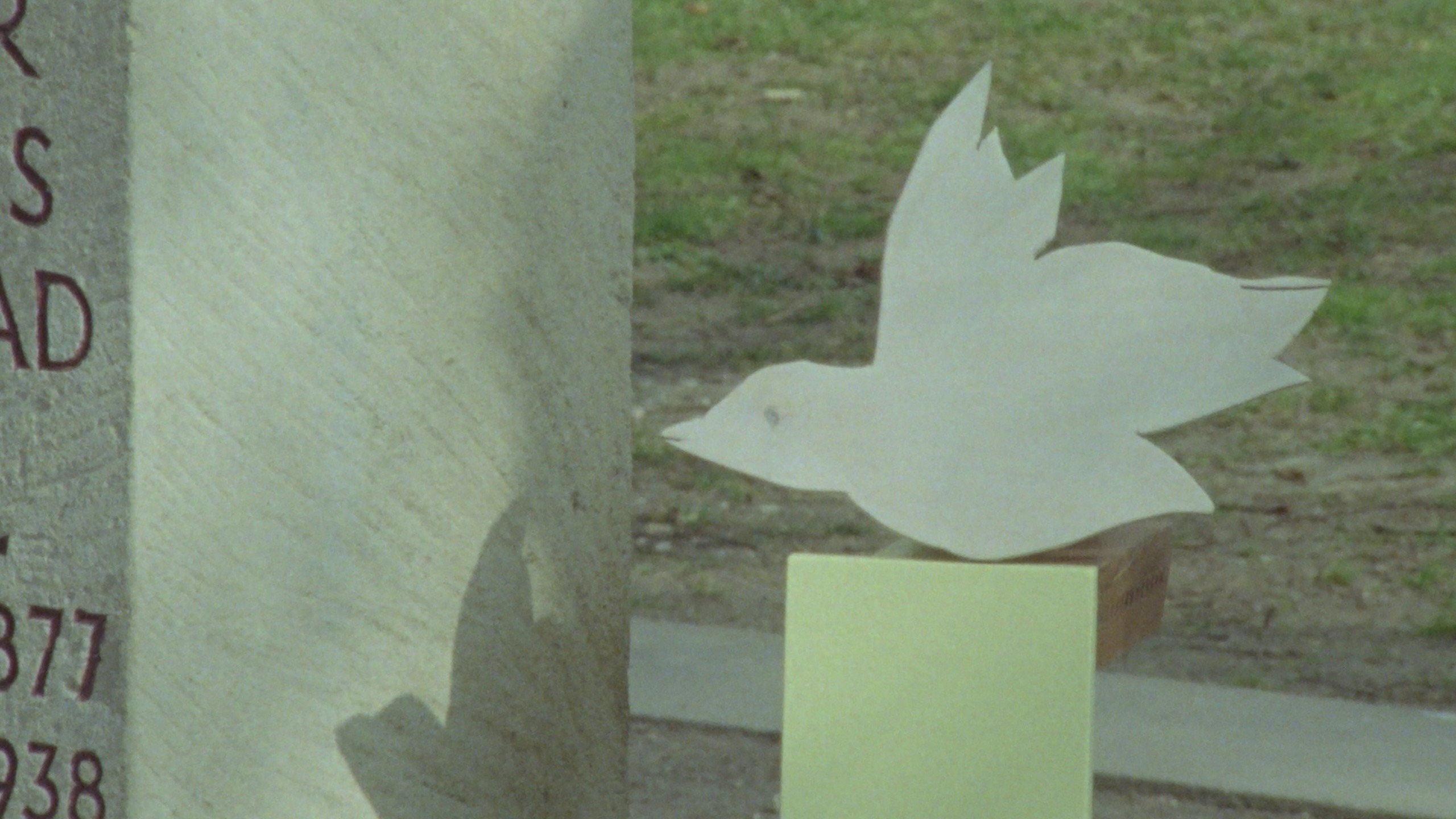 Photo: A stylized dove facing a monument or a thumbstone